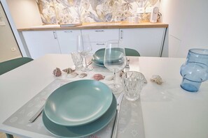 A dining table set with plates, glasses, and cutlery, with a decorative wall and a power outlet in the background. - Mare e Conchiglie - Studio Apartment, Sleeps 2 (Albenga)