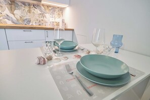 Ein Esszimmertisch ist gedeckt mit Tellern, Gläsern und Besteck, mit einer dekorativen Muschelkomposition.
