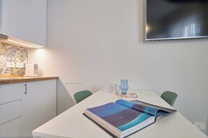 A modern dining area with a white table, two chairs, a book, a glass, and a decorative vase. - Mare e Conchiglie - Studio Apartment, Sleeps 2 (Albenga)