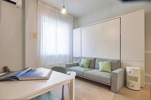Ein modernes Wohnzimmer mit einer Couch, einem Tisch mit einem Buch, einer Wand-Klimaanlage und einer Hängeleuchte.