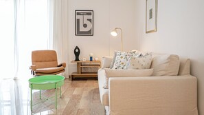 Ein Wohnzimmer mit einem beigen Sofa, einem grünen Sessel, einer Stehlampe und einem kleinen Tisch mit Dekoration.