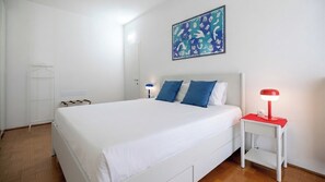 A hotel room with a bed, a nightstand with a lamp, a wardrobe, and a wall-mounted artwork. - Italianway Comfort - Torre 24 (Milano)