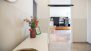 Eine moderne Küche mit dunklen Schränken, einer weißen Arbeitsplatte und einem Essbereich mit einem Holzsessel.