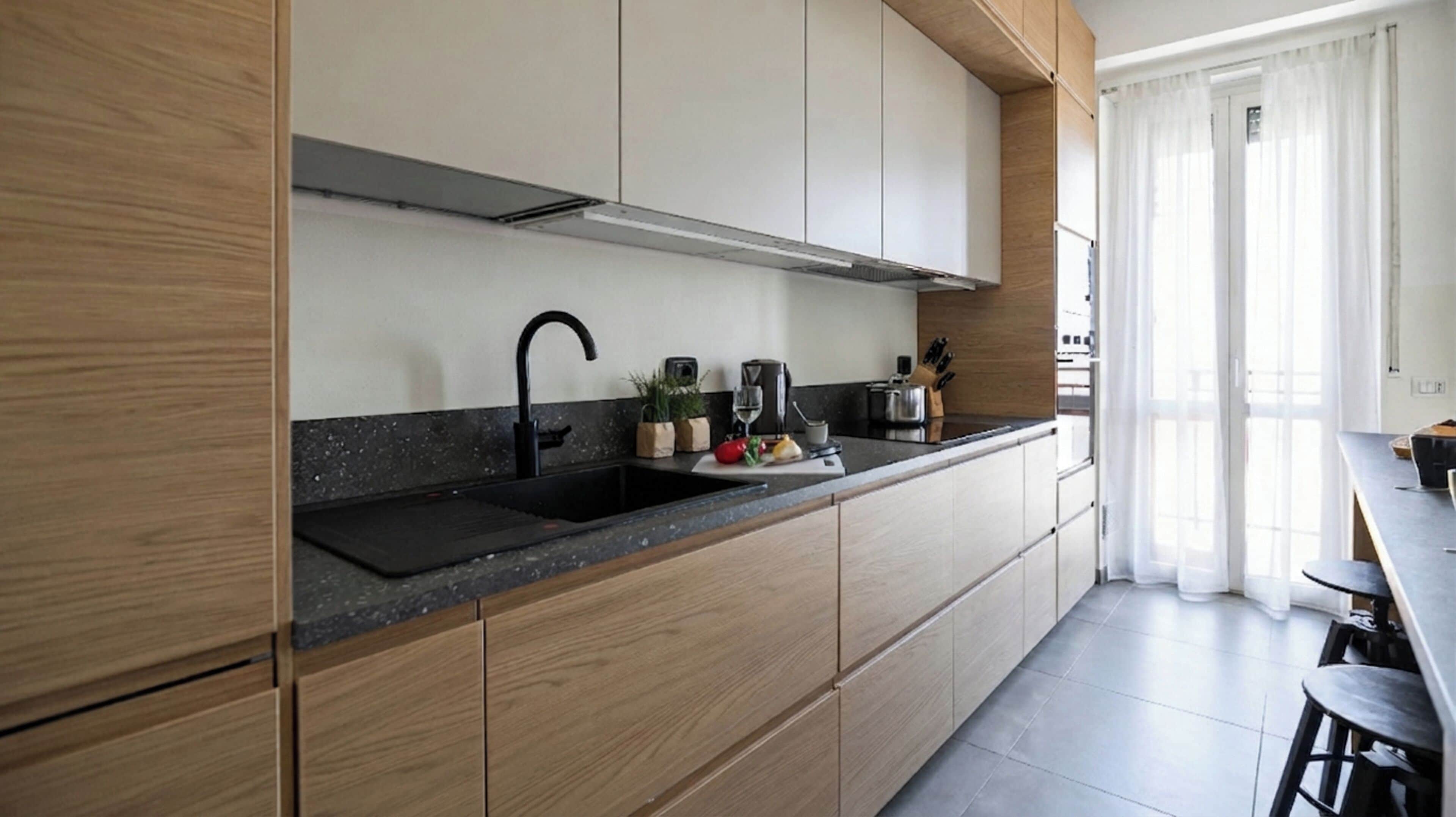 A modern kitchen with wooden cabinets, a black countertop, and a sink.