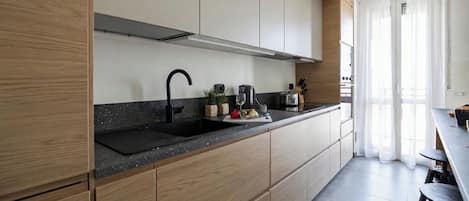 A modern kitchen with wooden cabinets, a black countertop, and a sink.