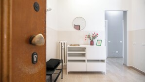 Ein modernes Interieur mit einer Holztür, einem weißen Konsolentisch mit Spiegel, einer Heizung und einer kleinen Bank.
