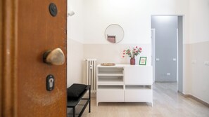 Ein modernes Interieur mit einer Holztür, einem weißen Konsolentisch mit Spiegel, einer Heizung und einer kleinen Bank.