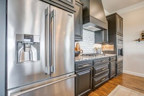 A modern kitchen with stainless steel appliances, dark cabinetry, and a marble countertop. - Gorgeous Lake View in Sportsman’s World (Strawn)