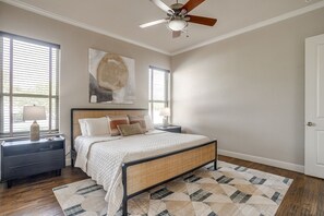 A bedroom with a bed, nightstands, a ceiling fan, and a large window with blinds. - Gorgeous Lake View in Sportsman’s World (Strawn)