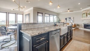 A modern kitchen with a marble countertop, black cabinetry, and pendant lighting. - Gorgeous Lake View in Sportsman’s World (Strawn)