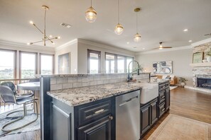 A modern kitchen with a marble countertop, black cabinetry, and pendant lighting. - Gorgeous Lake View in Sportsman’s World (Strawn)