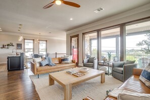A spacious living room with a large window, a ceiling fan, and a dining area with a table and chairs. - Gorgeous Lake View in Sportsman’s World (Strawn)