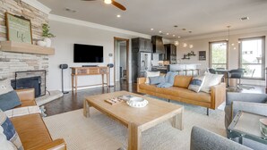 A modern living room with a fireplace, a television, and a dining area with bar stools. - Gorgeous Lake View in Sportsman’s World (Strawn)