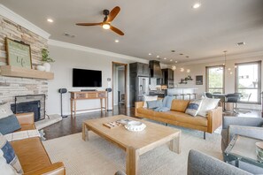 A modern living room with a fireplace, a television, and a dining area with bar stools. - Gorgeous Lake View in Sportsman’s World (Strawn)