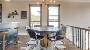 A dining area with a round table and chairs, a chandelier, and a view through large windows. - Gorgeous Lake View in Sportsman’s World (Strawn)