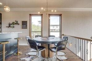 A dining area with a round table and chairs, a chandelier, and a view through large windows. - Gorgeous Lake View in Sportsman’s World (Strawn)