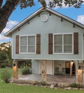 A two-story house with a front porch, stone columns, and a garage door.