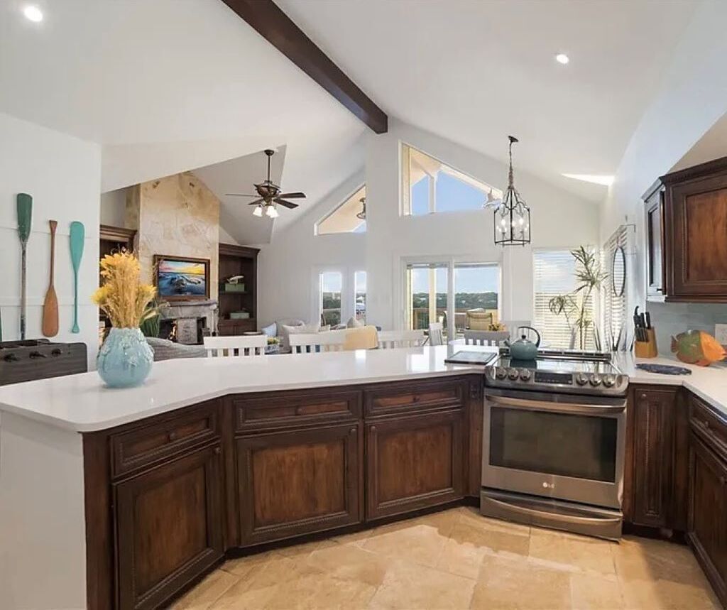 A spacious kitchen with a large island, dark wood cabinets, and a stainless steel stove.