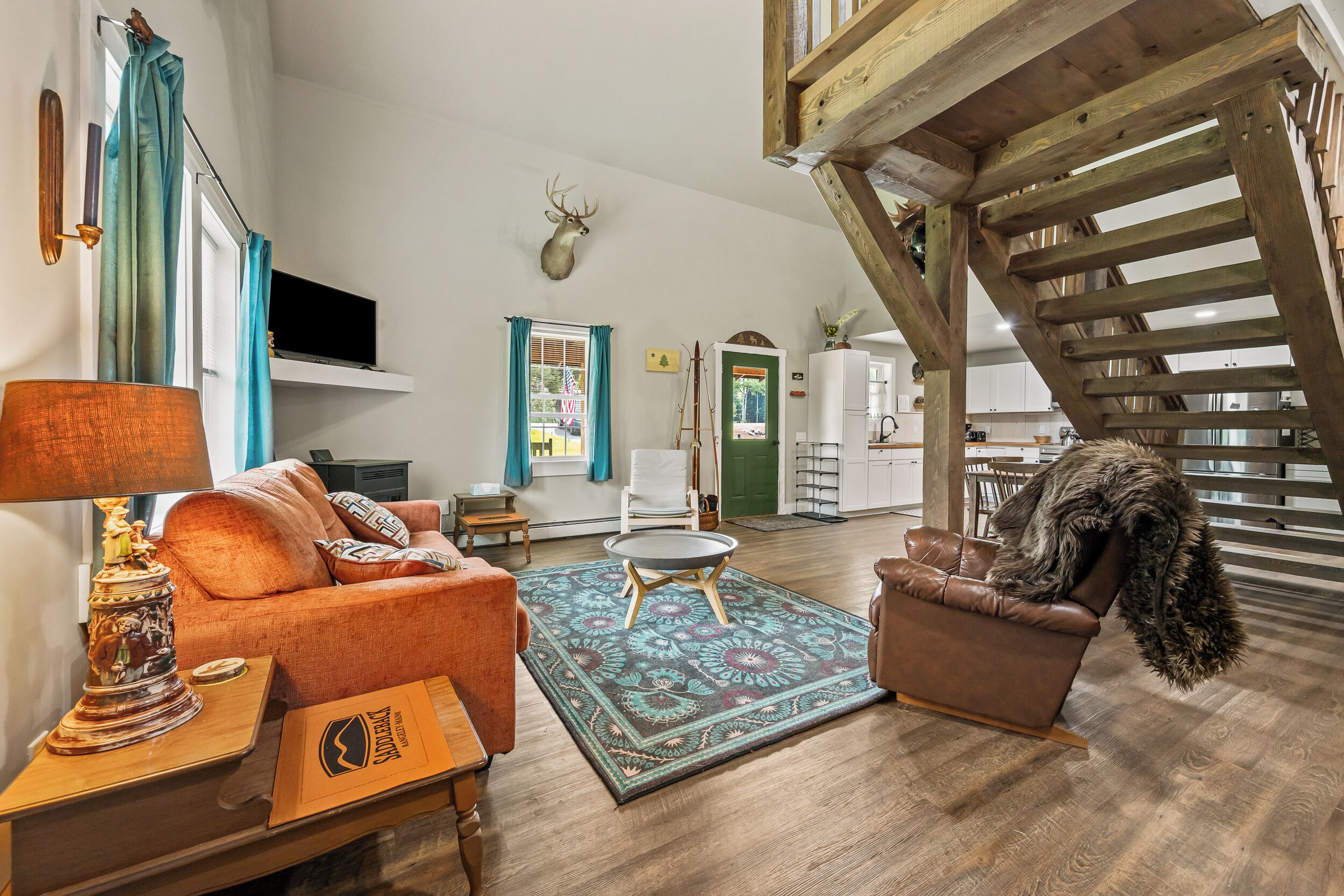 A spacious living room with a fireplace, a television, and a dining area with a staircase.