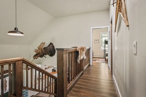 A wooden staircase with a railing, a mounted moose head, and a pendant light. - Hildy's Hideaway | NEW! Sleeps 10 | Direct Snowmobile Access | Near Saddleback & Downtown (Rangeley)