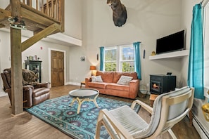 A cozy living room with a fireplace, a sofa, a coffee table, and a television. - Hildy's Hideaway | NEW! Sleeps 10 | Direct Snowmobile Access | Near Saddleback & Downtown (Rangeley)