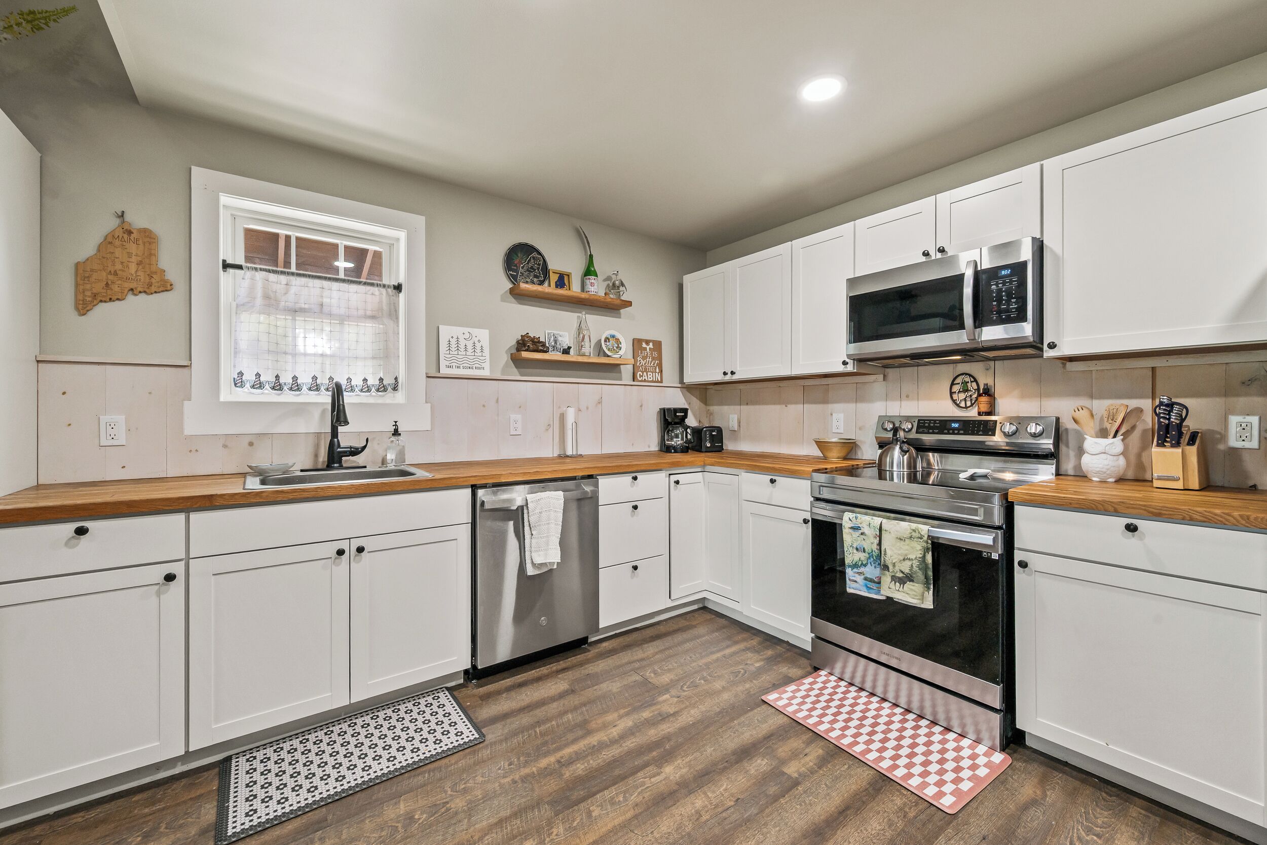 Cocina moderna con armarios blancos, electrodomésticos de acero inoxidable y encimeras de madera.
