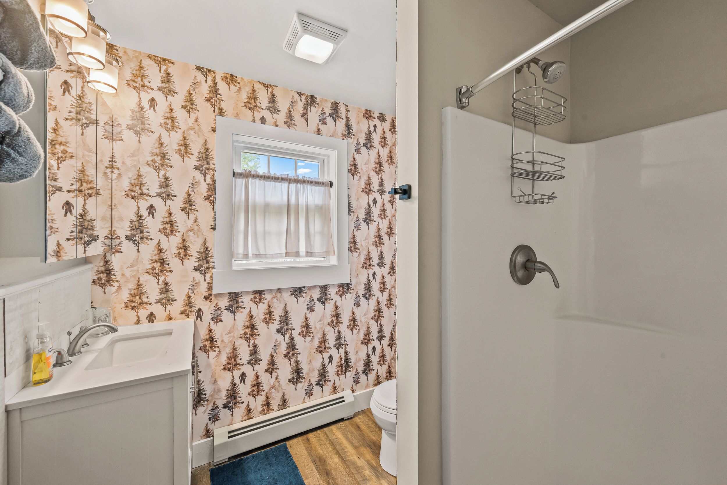 A bathroom with a window, a shower, and a sink.