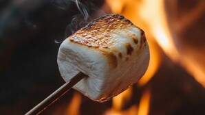A marshmallow on a stick over a fire.