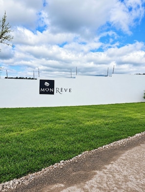 A sign with 'MON RÉVE' on a white wall, a grassy field, and a cloudy sky. - mon Reve Estate (Paarl)