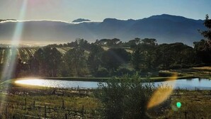 A landscape with a body of water, trees, and distant mountains under a clear sky.
