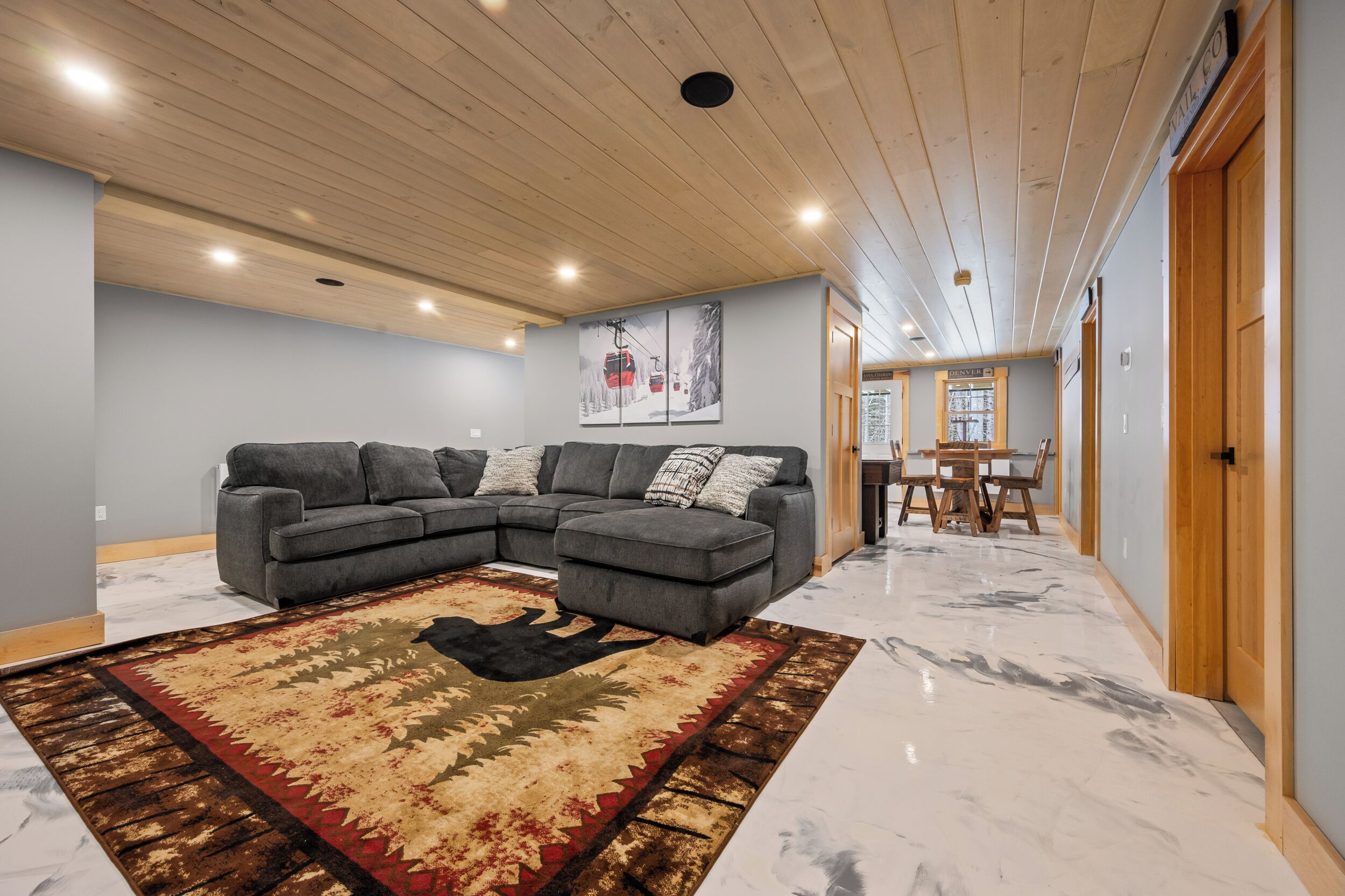 Una sala moderna con un sofá modular, un tapete estampado y una zona de comedor con una mesa y sillas de madera.