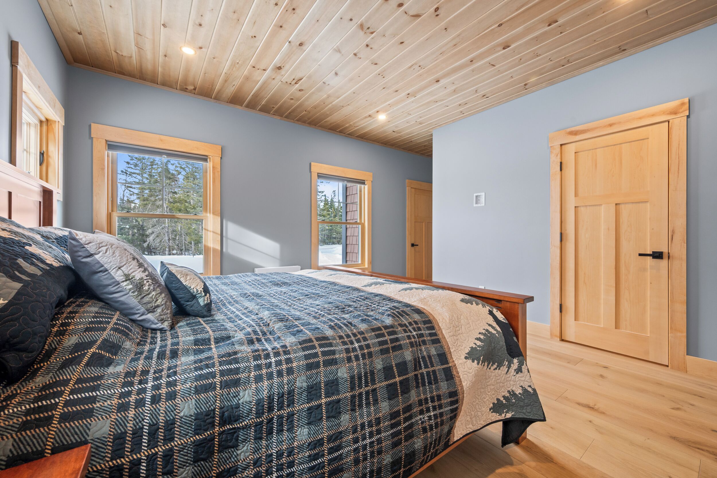 Ein Schlafzimmer mit einem großen Bett, Holzboden und zwei Fenstern.