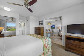 Ein Hotelzimmer mit einem Bett, einem Fernseher, einem Deckenventilator und Blick ins Freie.