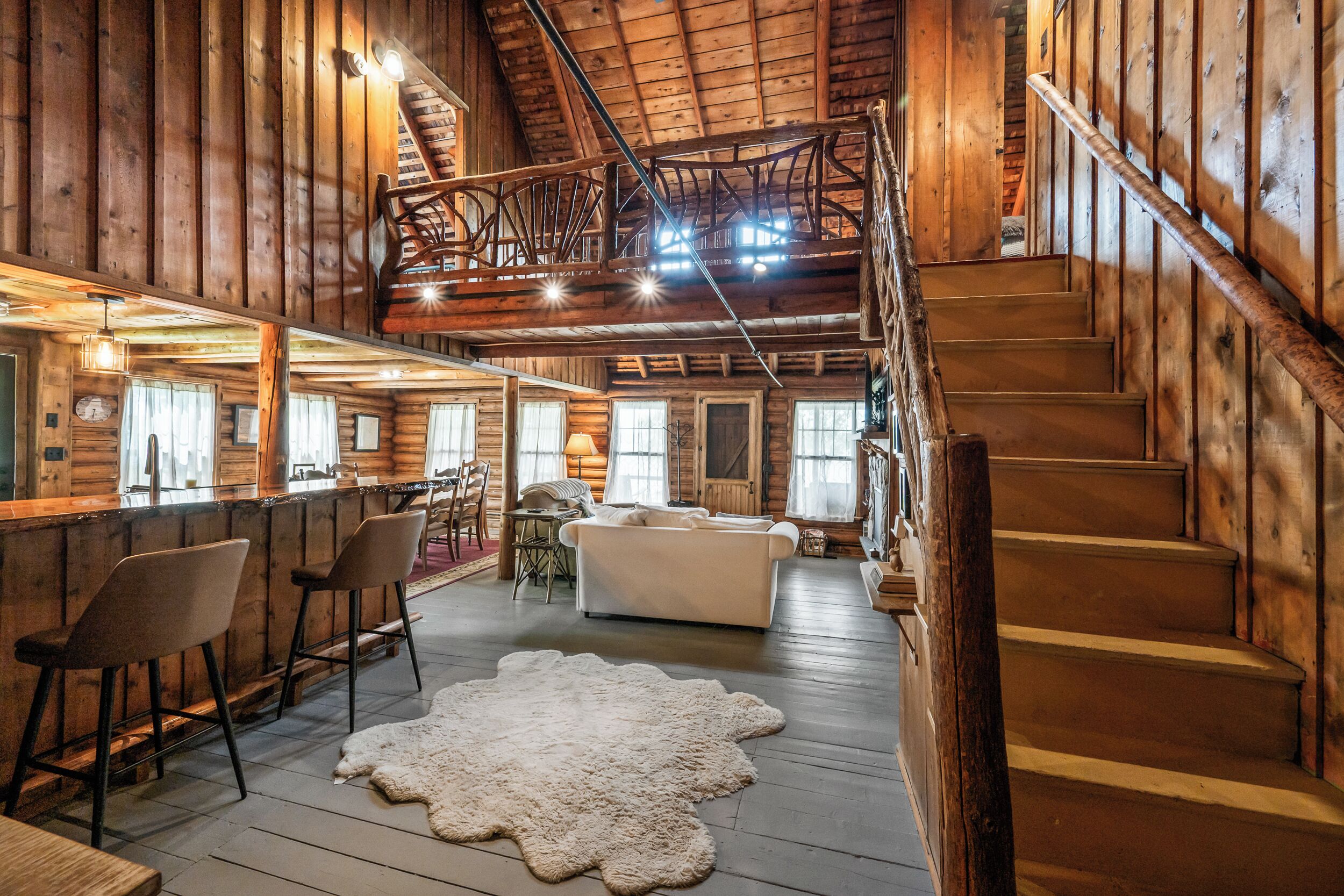 A log cabin interior with a dining area, a staircase, and a living room.