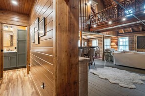 A log cabin interior with a kitchen, dining area, and living room.