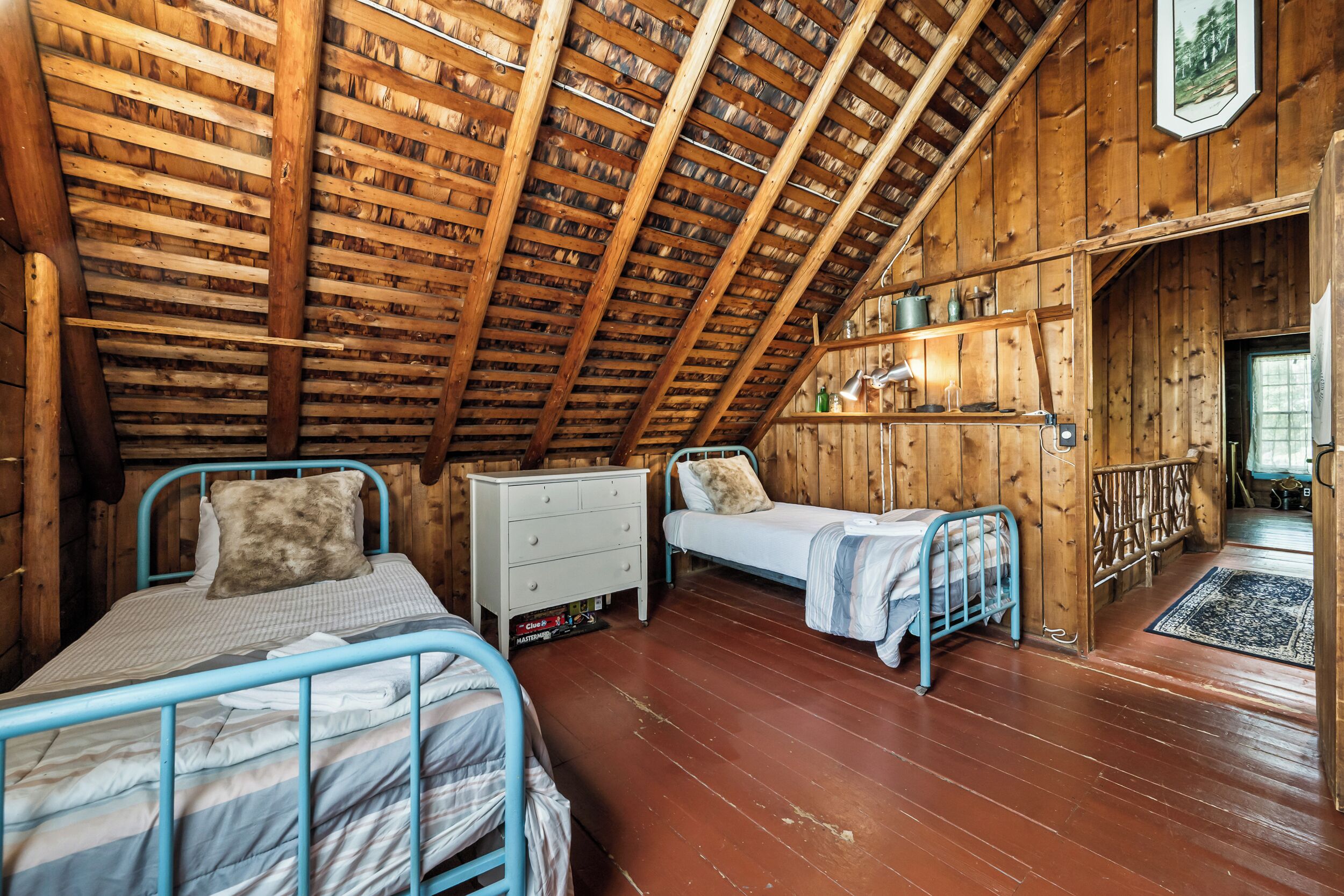 Ein gemütliches Schlafzimmer im Dachgeschoss mit zwei Betten, einem Schminktisch und einem Regal mit diversen Gegenständen.