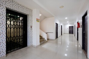 Pasillo de hotel con pared de baldosas, una escalera y un extintor.