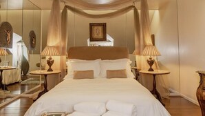 A hotel room with a large bed, two bedside tables with lamps, a mirror, and a picture on the wall.