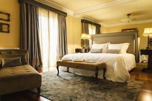 A hotel room with a large bed, a sitting area, and a view of the outdoors.