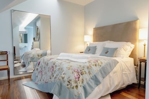 A hotel room with a large bed, two bedside tables, a mirror, and a wooden floor. - Estrepão House (Guimaraes)