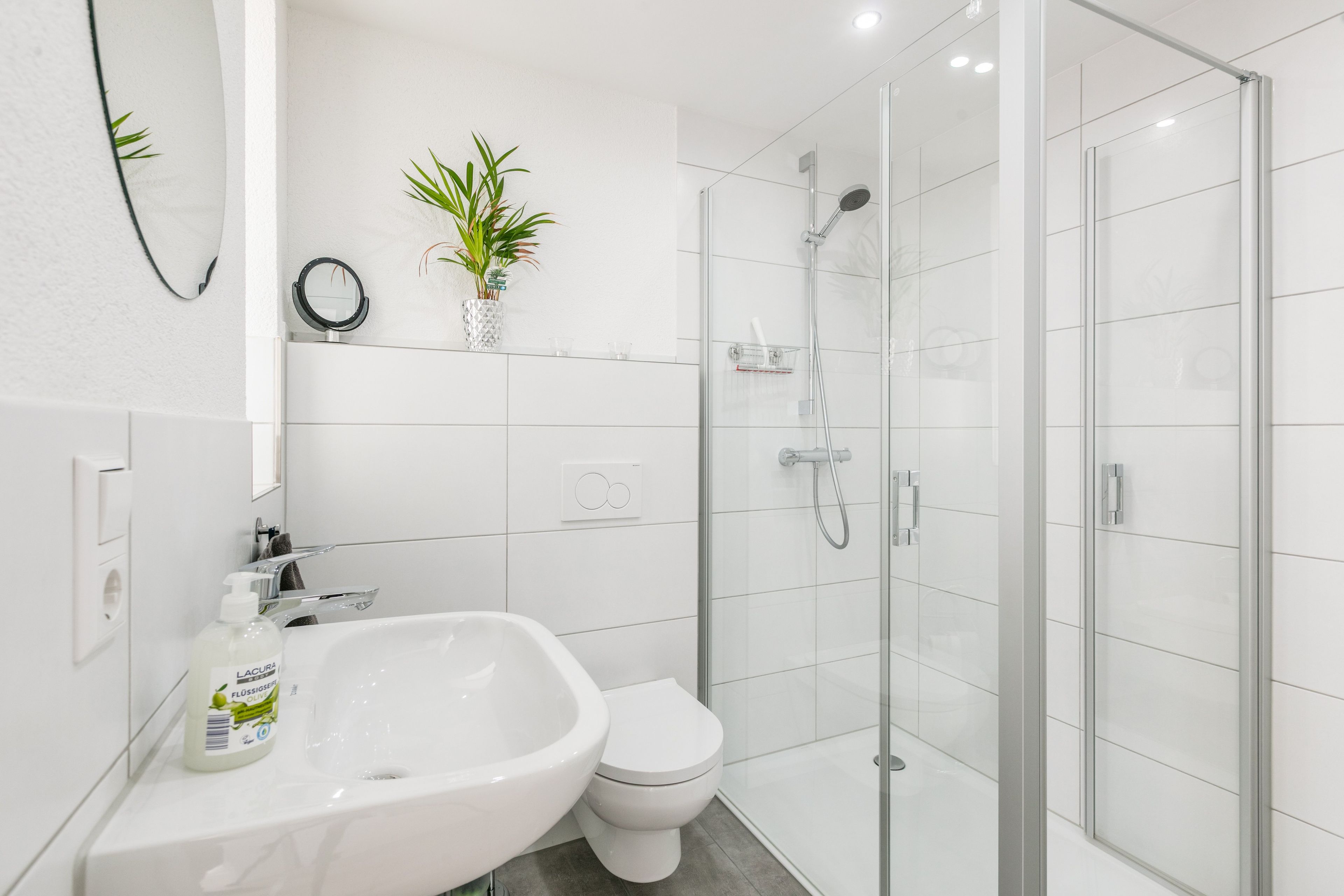Une salle de bain moderne avec une douche à parois de verre, un lavabo blanc et des toilettes.