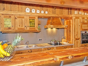 A wooden kitchen with a built-in stove, a sink, and a fruit bowl on the counter.