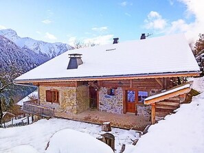 Eine Berghütte mit Steinaußenwand, Holzverkleidung und verschneietem Dach.