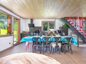 Ein Essbereich mit einem Tisch für sechs Personen, eine Küche im Hintergrund und eine Treppe mit bunten Flaggen.
