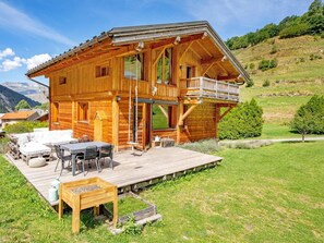 Eine Holzchalet mit einer Terrasse, Gartenmöbeln und einer malerischen Bergkulisse.