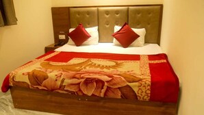 A bed with a floral bedspread, a headboard, and two red pillows. - MM TAJ STAY (Fatehabad)