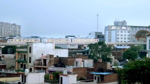 A multi-story building with a flat roof, a visible sign for 'GMCC,' and a bridge with a curved arch overhead. - MM TAJ STAY (Fatehabad)