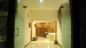 A hotel lobby with a reception desk, a staircase, and a seating area. - MM TAJ STAY (Fatehabad)