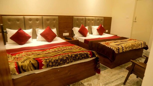 A hotel room with two beds, each with a headboard and pillows. - MM TAJ STAY (Fatehabad)