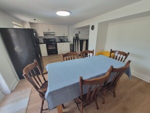 A dining area with a table covered in a blue tablecloth, surrounded by wooden chairs. - Spacious | Private | Quiet | 2 BR Walkout Suite (Aurora)